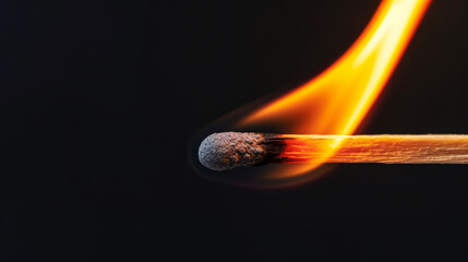 Close-up of a burning wooden match with vibrant flame against a black background