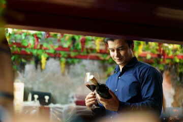 Portrait of good looking caucasian man testing and examining a red wine.