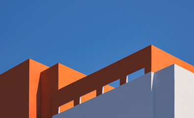 Geometric architecture pattern of high section of modern orange and white building with sunlight...