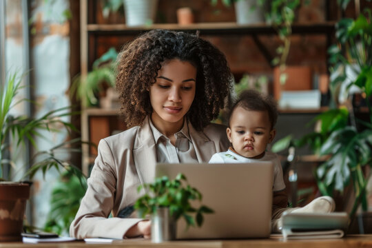 A professional woman dressed in a sleek suit, balancing her role as a mother and business owner by holding her child and using a laptop in a modern home office. - Powered by Adobe