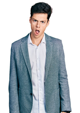 Young hispanic man wearing business clothes in shock face, looking skeptical and sarcastic, surprised with open mouth