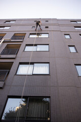 高層マンションの窓掃除をしている、命綱をした清掃業者