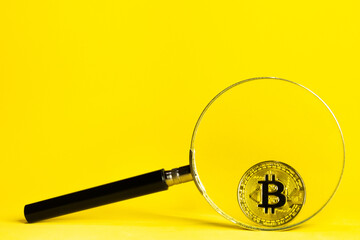 a magnifying glass and a bitcoin cryptocurrency behind it on a yellow background,concept of web3 search and blockchain technology