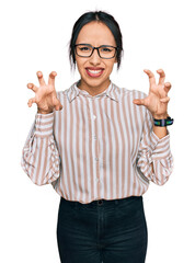 Young hispanic girl wearing casual clothes and glasses smiling funny doing claw gesture as cat,...