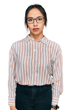 Young hispanic girl wearing casual clothes and glasses relaxed with serious expression on face. simple and natural looking at the camera.