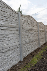 Concrete fence from panels. Decorative fence with a gray panel fence in the garden. Textured 