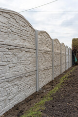 Concrete fence from panels. Decorative fence with a gray panel fence in the garden. Textured 
