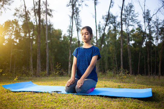 Thunderbolt Pose or Diamond Pose or vajrasana, indian young women meditating in the forest with eyes closed doing Kneeling Prayer Pose yoga
