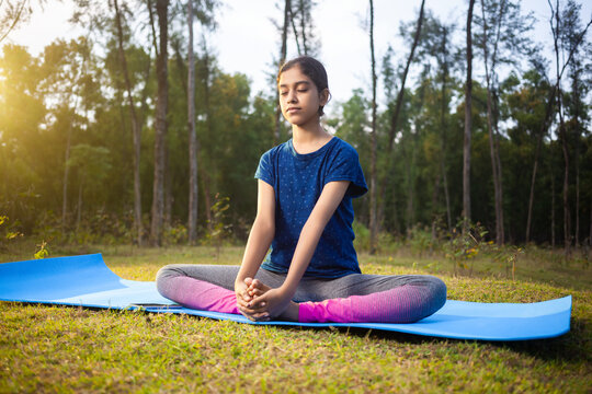 indian slim women practicing baddha konasana or cobbler pose or butterfly pose yoga in the calm nature during sunrise