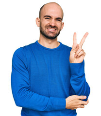 Young hispanic man wearing casual clothes smiling with happy face winking at the camera doing...