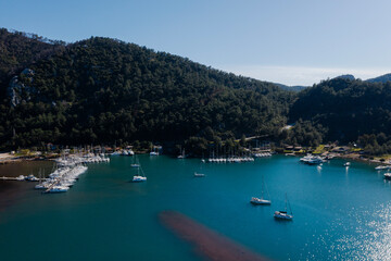 Fototapeta na wymiar Aerial view of boats and beautiful city in Marmaris, Turkey. Landscape with boats in marina bay, sea, city lights, mountains. Top view from drone. 