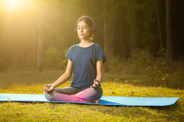 asian athlete women meditating in a zen-like position or padmasana pose while listening to music on...