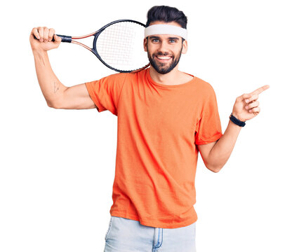Young handsome man with beard playing tennis holding racket smiling happy pointing with hand and finger to the side