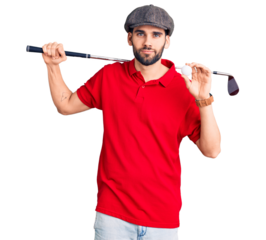Young handsome man with beard playing golf holding club and ball thinking attitude and sober expression looking self confident