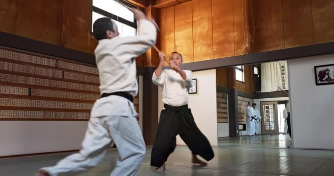 Aikido with sensei, wooden sword and student training for fitness, fight and action in dojo. Teaching, learning and men in traditional Japanese martial arts class with aikidoka, bokken and challenge.