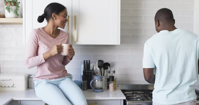 A diverse couple enjoys a conversation in a modern kitchen