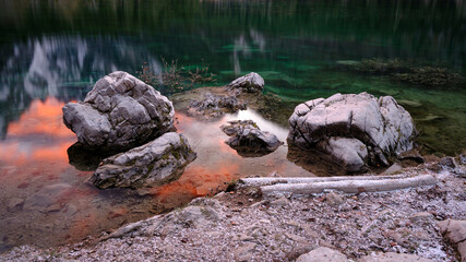 rocks in lake with reflections of mountains at sunset