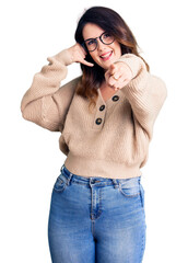 Beautiful young brunette woman wearing casual clothes and glasses smiling doing talking on the...