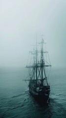 Fototapeta premium A ghostly sailing pirate ship emerges from a dense fog on the open sea, creating a mysterious and eerie maritime scene.