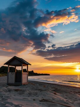 A serene beach at sunset, featuring a lifeguard hut, calm waves, and a sky painted with hues of orange and blue.
