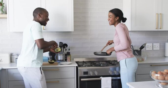 A diverse couple is cooking breakfast together in a modern kitchen