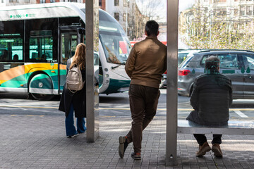 Three people waiting for the city bus. Pamplona