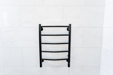 Furniture A black cylinder towel rack hangs on a white tiled wall