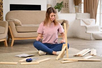 A young woman enthusiastically assembles a rack or shelf according to instructions that have errors