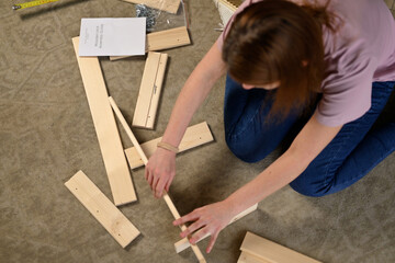 Top view of woman assembling shelving process at home according to instructions