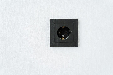 A rectangle black wall socket on a white wall, a stylish metal fashion accessory