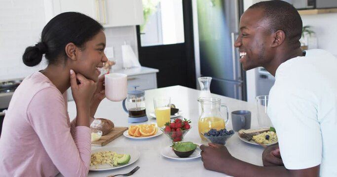 A diverse couple enjoys a breakfast together at home in the kitchen