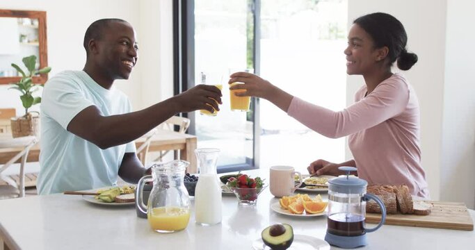 A young African American couple enjoys breakfast together at home in the kitchen
