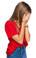 Teenager caucasian girl wearing casual red t shirt with sad expression covering face with hands while crying. depression concept.