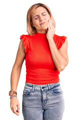 Young blonde woman wearing casual clothes touching mouth with hand with painful expression because of toothache or dental illness on teeth. dentist