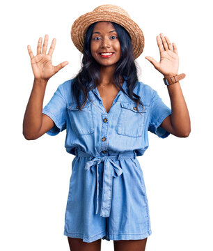 Young indian girl wearing summer hat showing and pointing up with fingers number ten while smiling confident and happy.