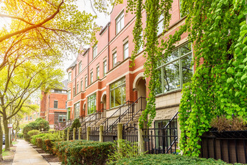 Row of modern brick town houses along a tree lined sidewalk on a sunny spring day