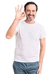 Fototapeta premium Middle age handsome man wearing casual t-shirt smiling positive doing ok sign with hand and fingers. successful expression.