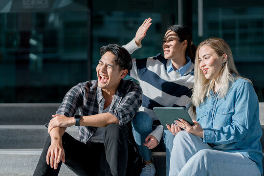 Group of happy young diverse colleagues talking and having fun together outdoors on college campus. Happy teenage students talking outside high school building. People in their leisure time.