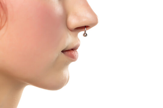Closeup of a young serious woman's visage with piercing septum hanging from her nose. Side voew.