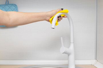 woman wiping faucet with rag in kitchen