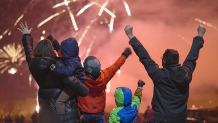 Excited happy family with kids watch and enjoy the New Year Eve night fireworks show