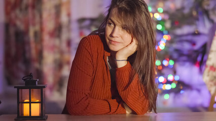 Young pretty woman near lantern waits for Santa in front of Christmas tree