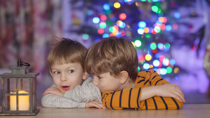 Cute little brothers waiting for Santa Claus in front of Christmas tree