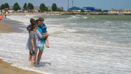 Fototapeta na wymiar Big young family on beach admiring the wild waves of the sea