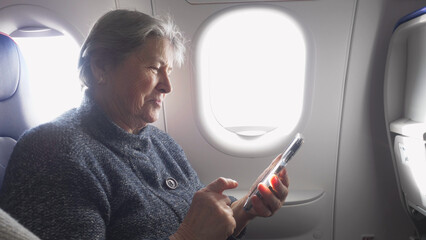 Old woman watching the mobile phone in airplane