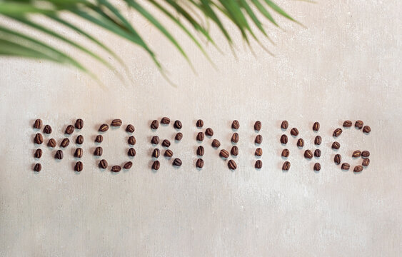 Lettering with coffee beans - morning greeting, on wooden surface