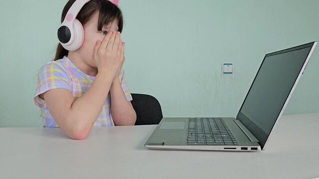 Little girl closes her eyes in fear while using a laptop. Internet security