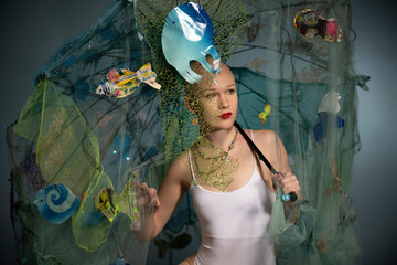 A woman poses with a white dress, surrounded by a net with sea creature decorations