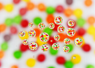 Assorted pieces of bright colorful round candy shot through water drops on white background