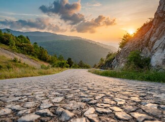 Low level view of empty old paved road in mountain area at sunset